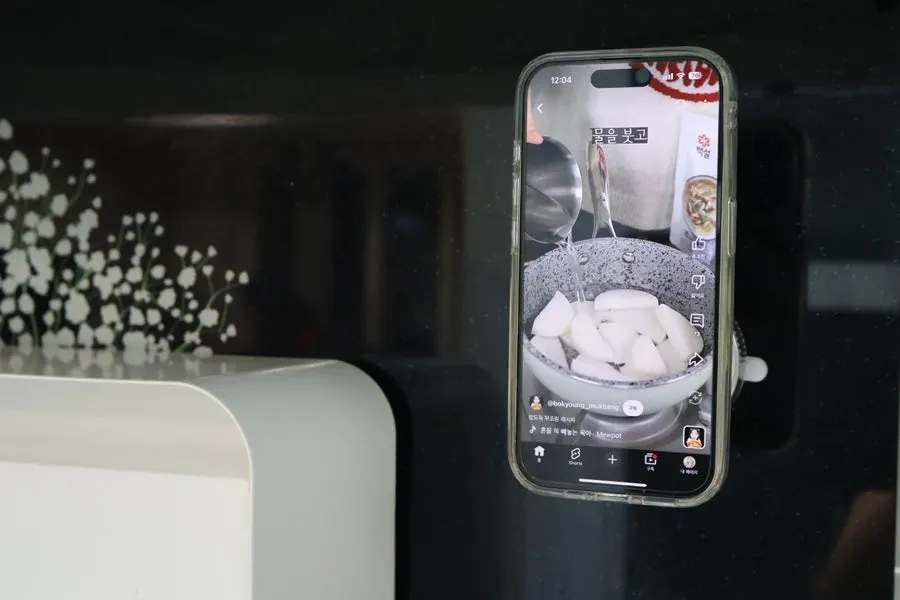 Stand showing a recipe video on sink tiles