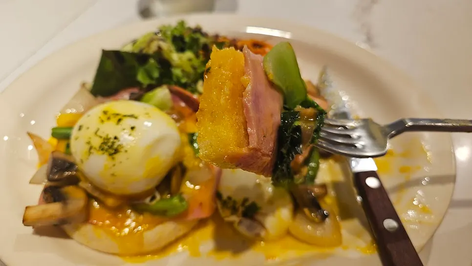 Eggs Benedict topped with poached egg and prosciutto