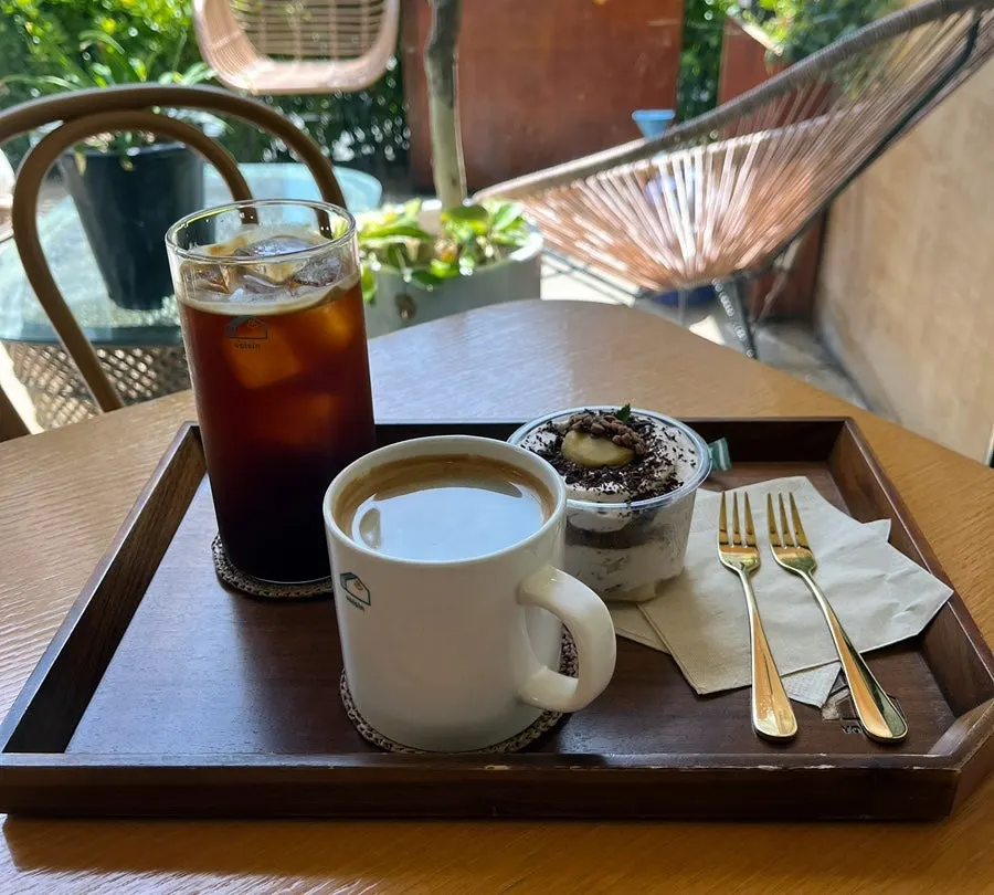 Coffee and dessert on a table surrounded by plants