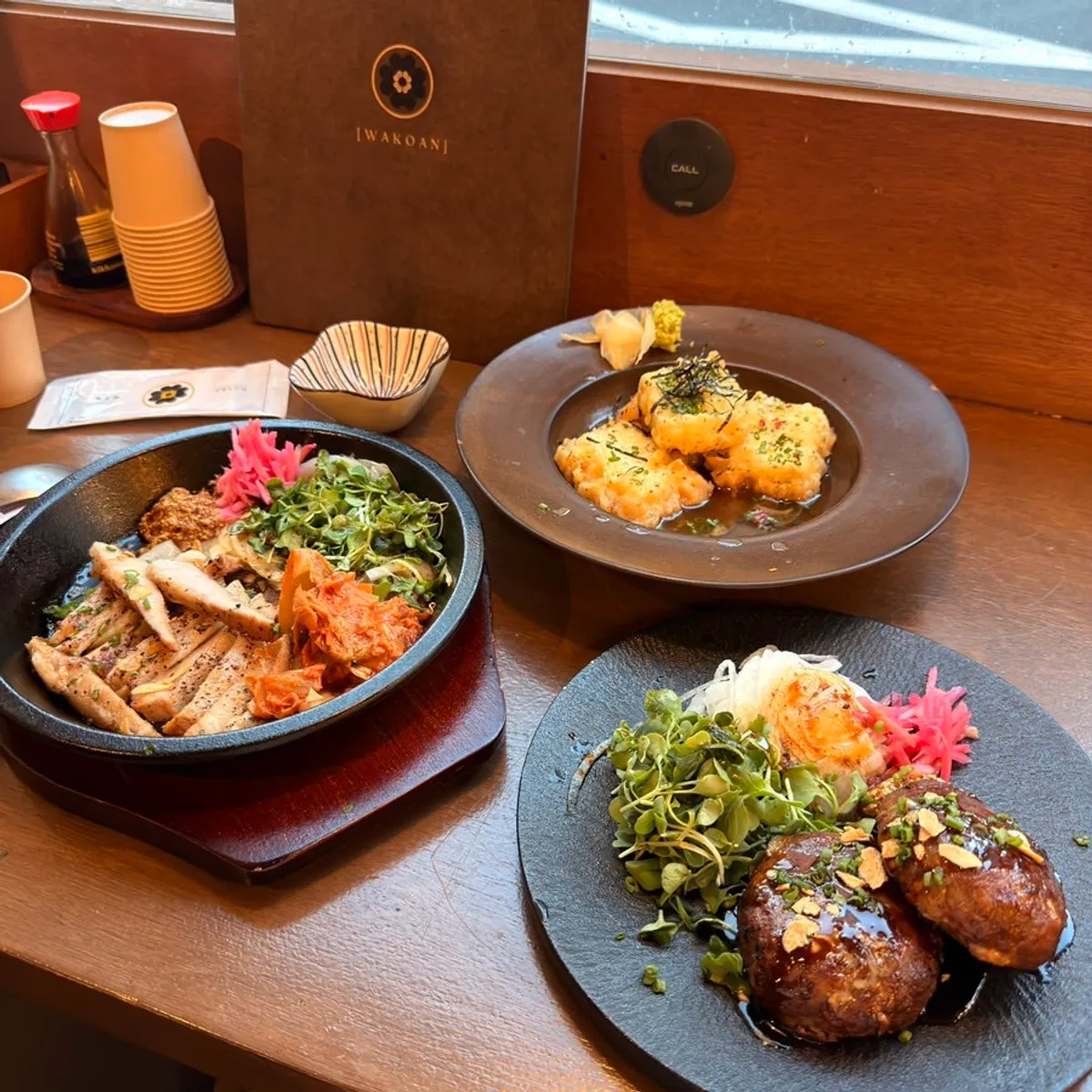 Table spread of pork jowl steak, tteokgalbi, and agedashi tofu