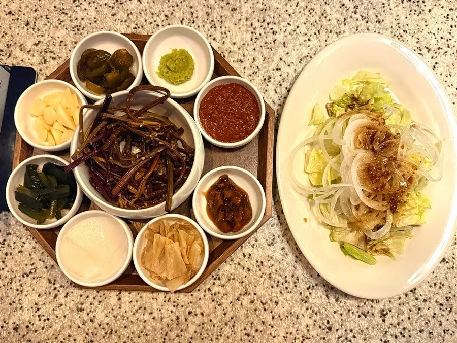 Side dishes including bracken fern, radish wraps, and salad