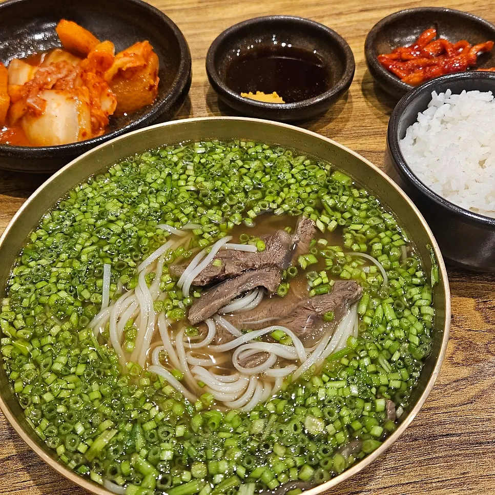 Minari rice noodle soup served in a brass bowl with the full spread