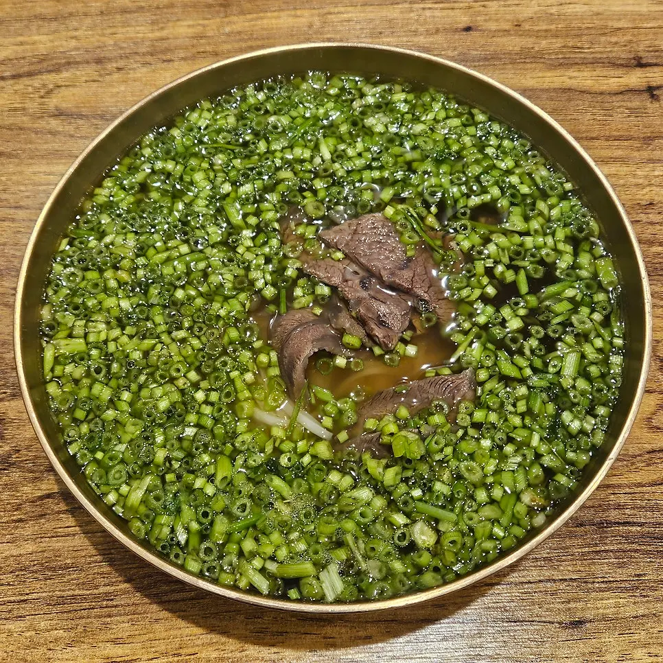 Finely chopped minari covering the surface of the broth