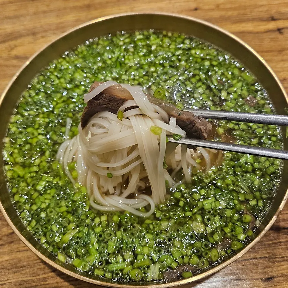 Noodles and meat lifted together with chopsticks