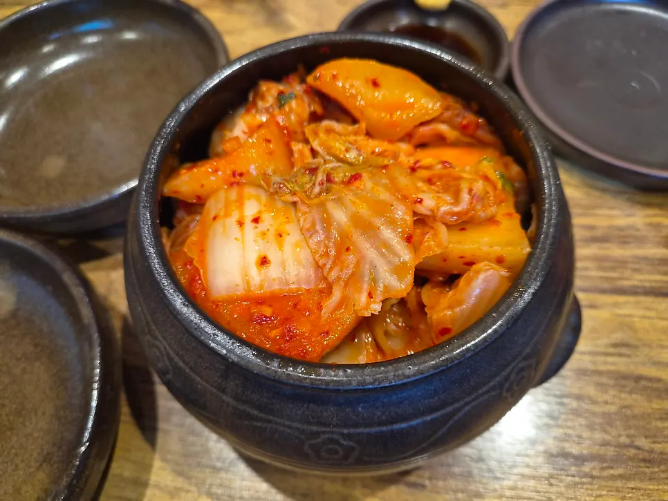 Sauce, dried radish strips, and kimchi and diced radish kimchi in earthenware bowls