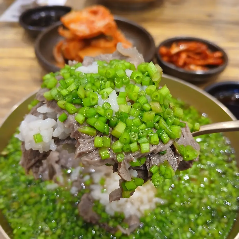 A spoonful of gomtang topped with finely chopped minari