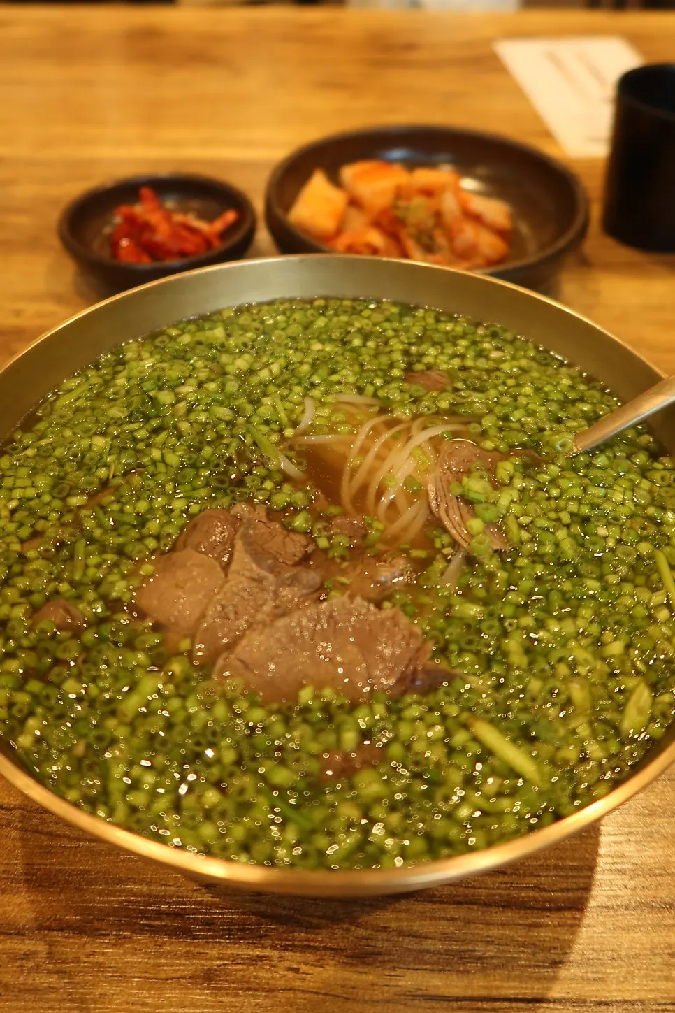 A large bowl of minari rice noodle soup at Geumnyeong Gomtang