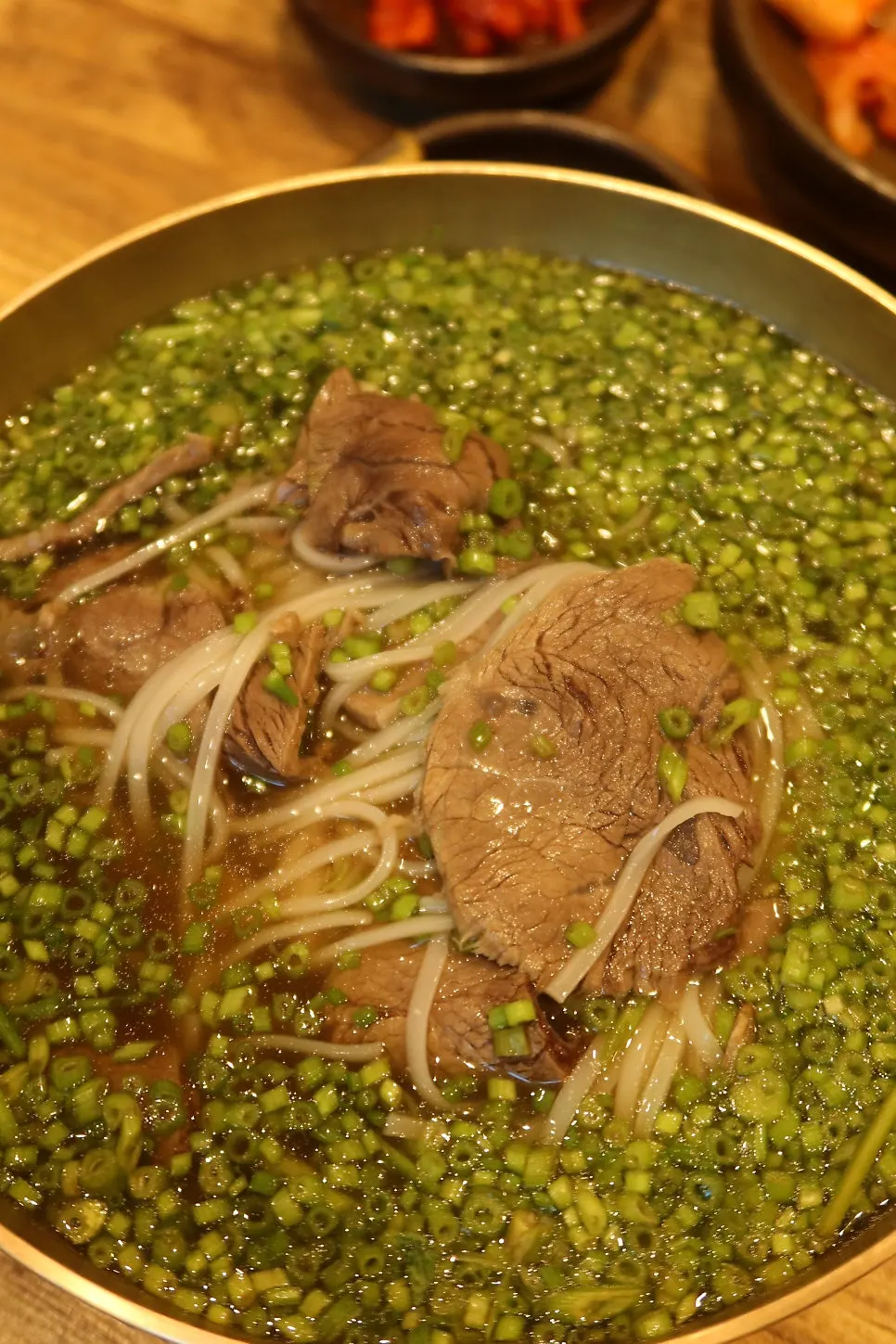 Gomtang rice noodle soup piled with minari