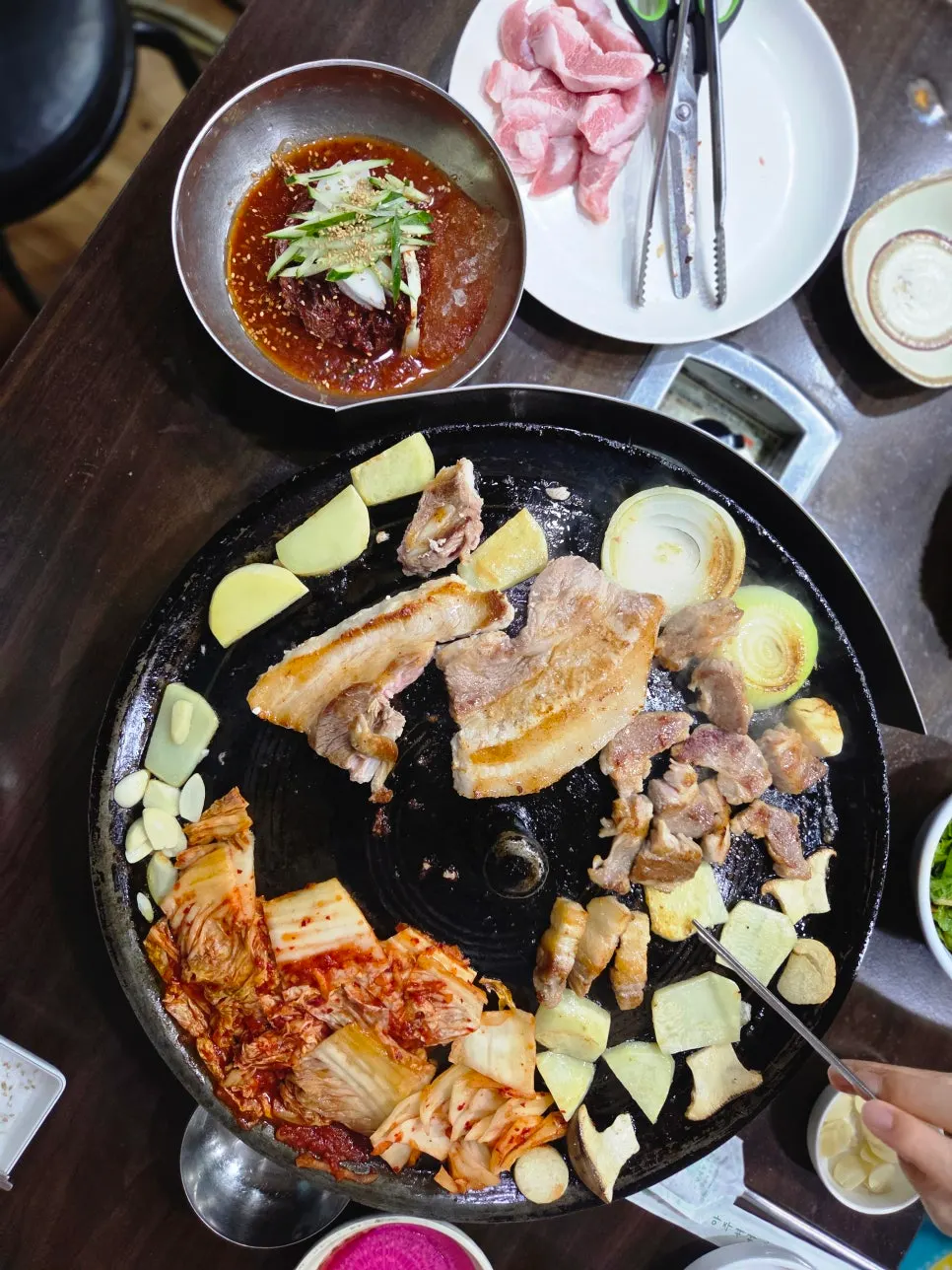 Staff placing meat on the cauldron-lid griddle to grill
