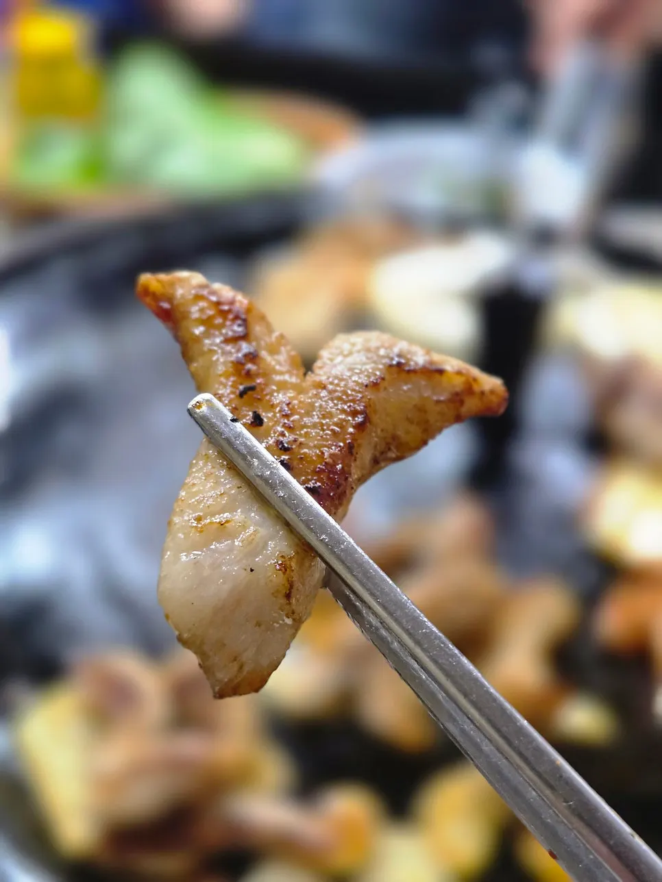 Pork belly turning golden brown on the cauldron-lid griddle