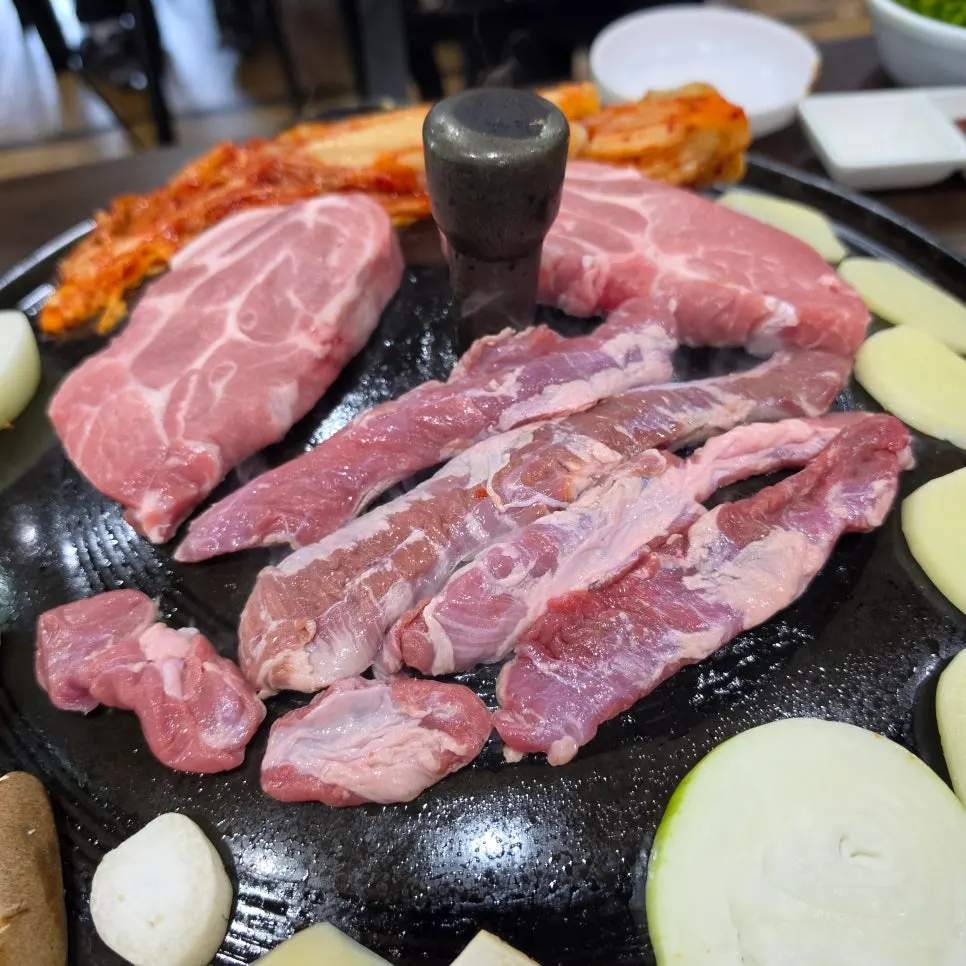 Three servings of pork placed on the cauldron lid