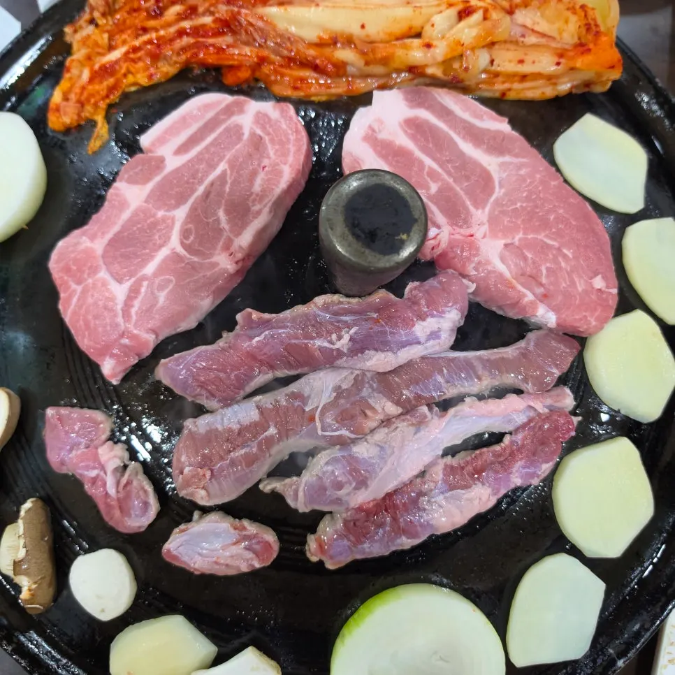 Meat cooking on the heated cauldron lid