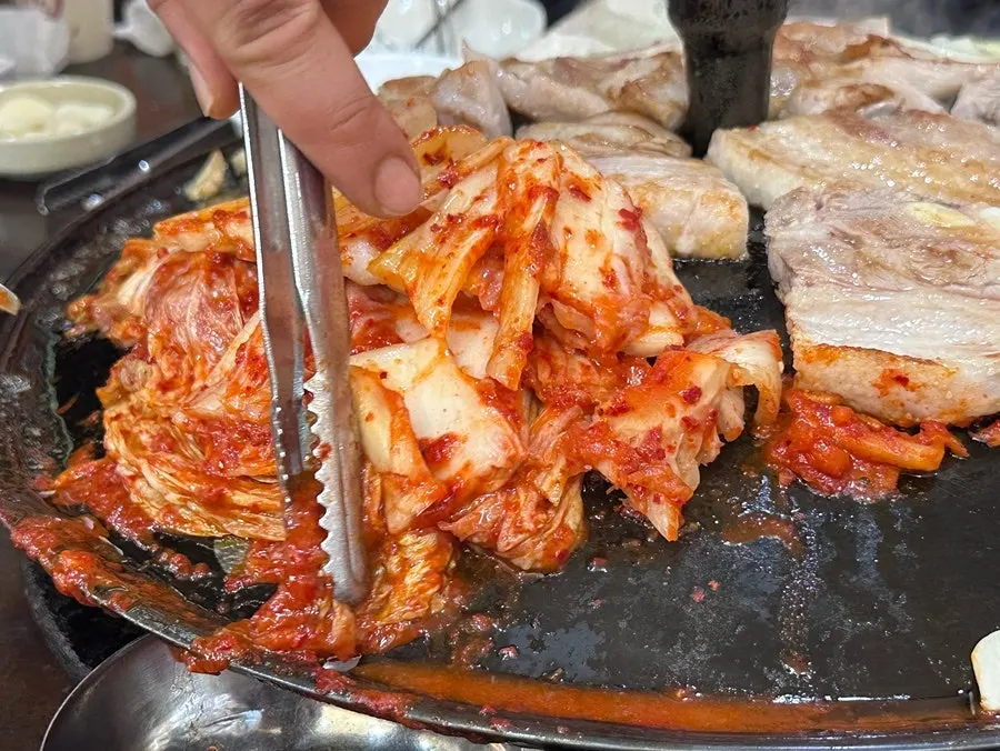 Sliced pork belly grilled alongside kimchi