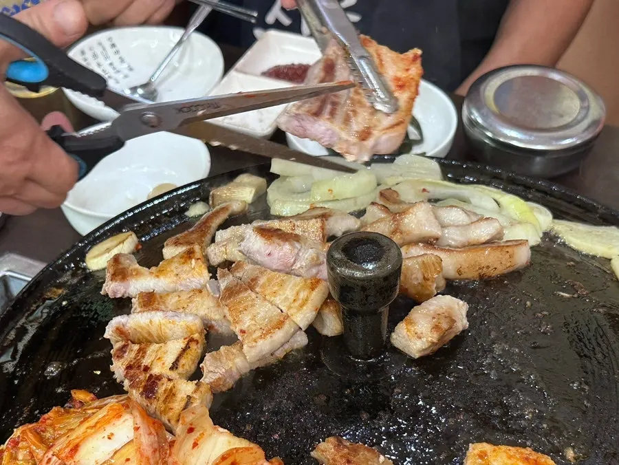 Kimchi and meat grilling on the cauldron lid