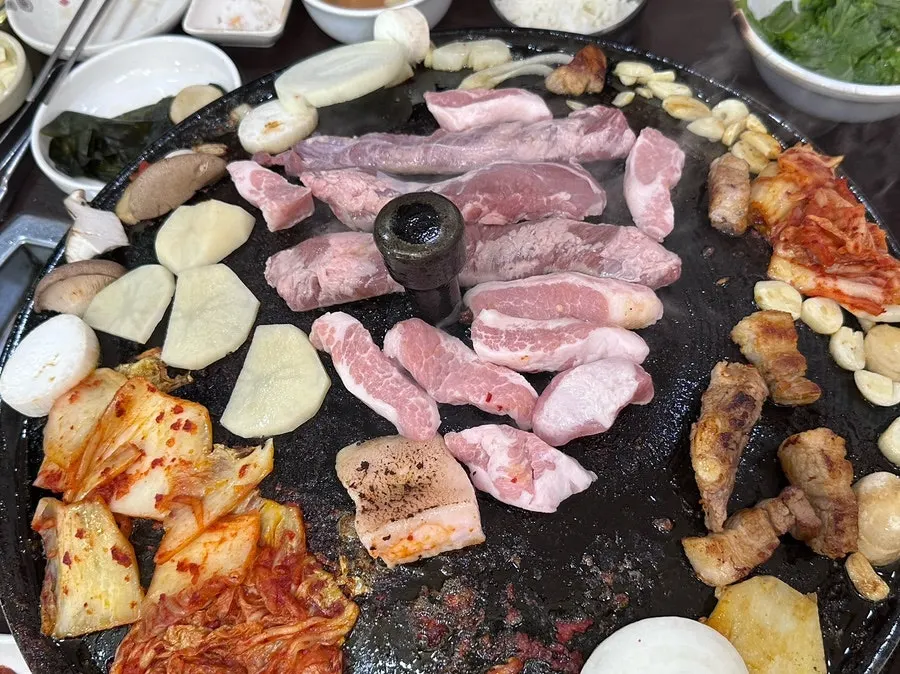 Specialty cuts of meat grilling on the cauldron lid