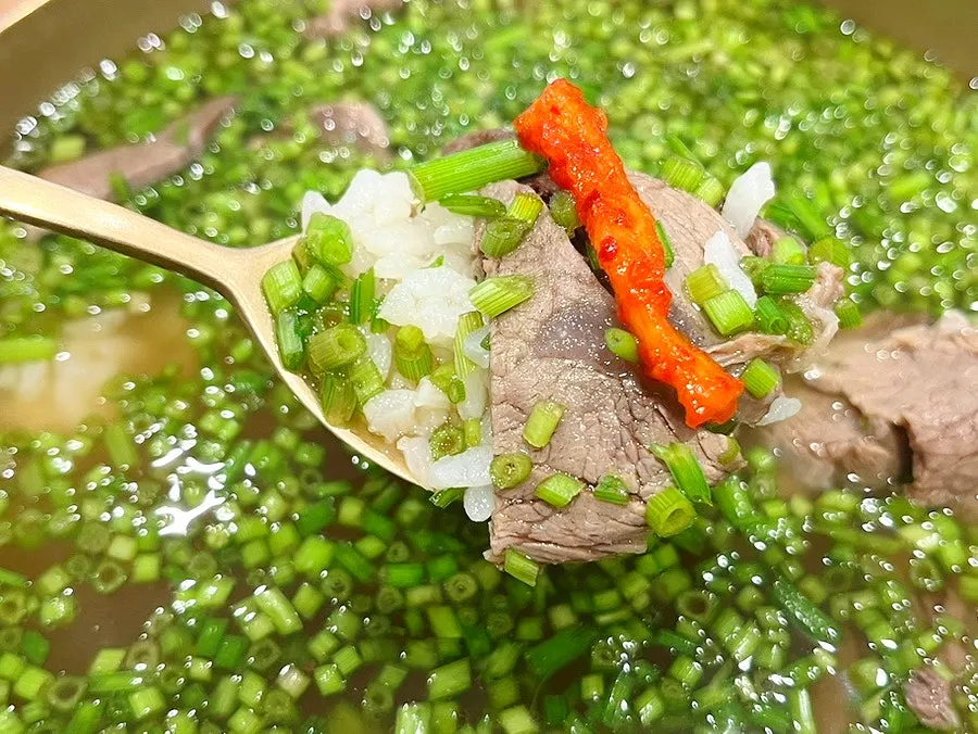 A spoonful of gomtang meat and rice lifted from the bowl