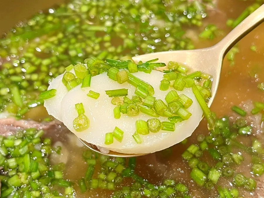A spoonful of gomtang topped with radish strips and seokbakji