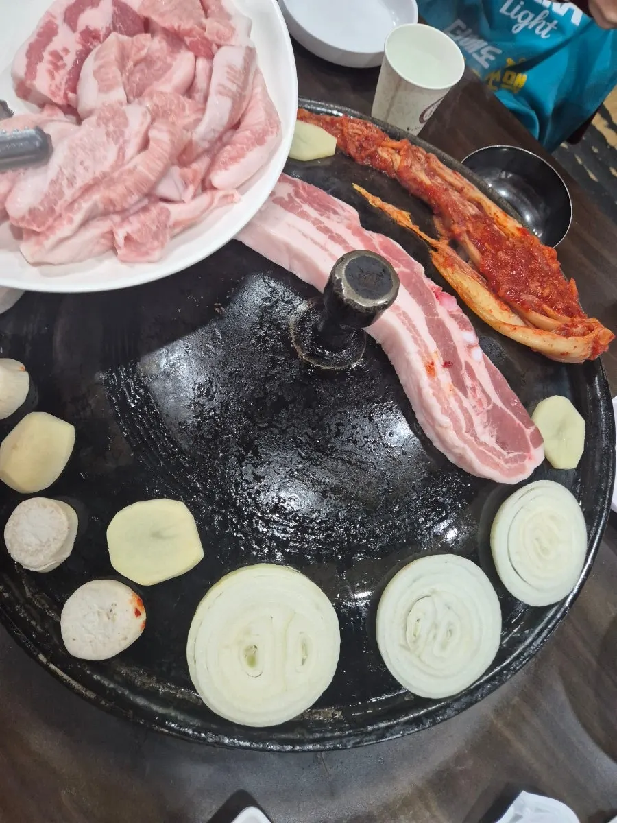 솥뚜껑 위 삼겹살과 감자 사진