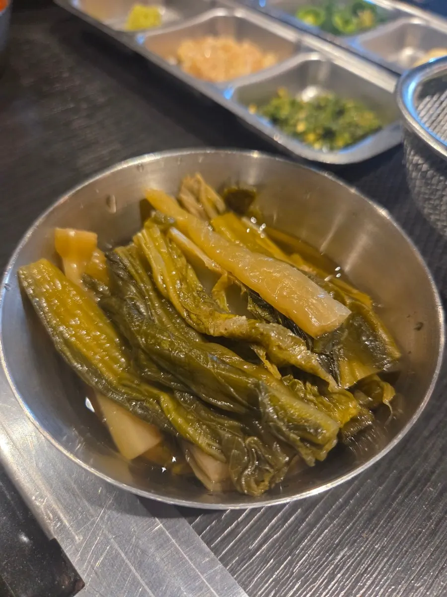 A bite of meat paired with pickles and radish salad