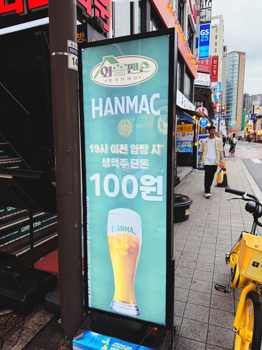 Sign announcing ₩100 draft beer happy hour before 7pm