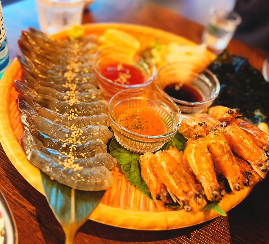 Raw shrimp sashimi served with soy sauce, chogochujang, buldak sauce and lemon