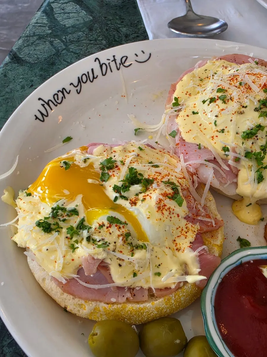 Egg Benedict with the poached egg broken open and hollandaise sauce