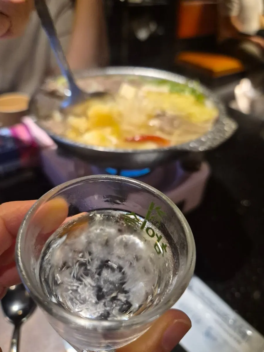 煮えている水肉チゲと焼酎グラス