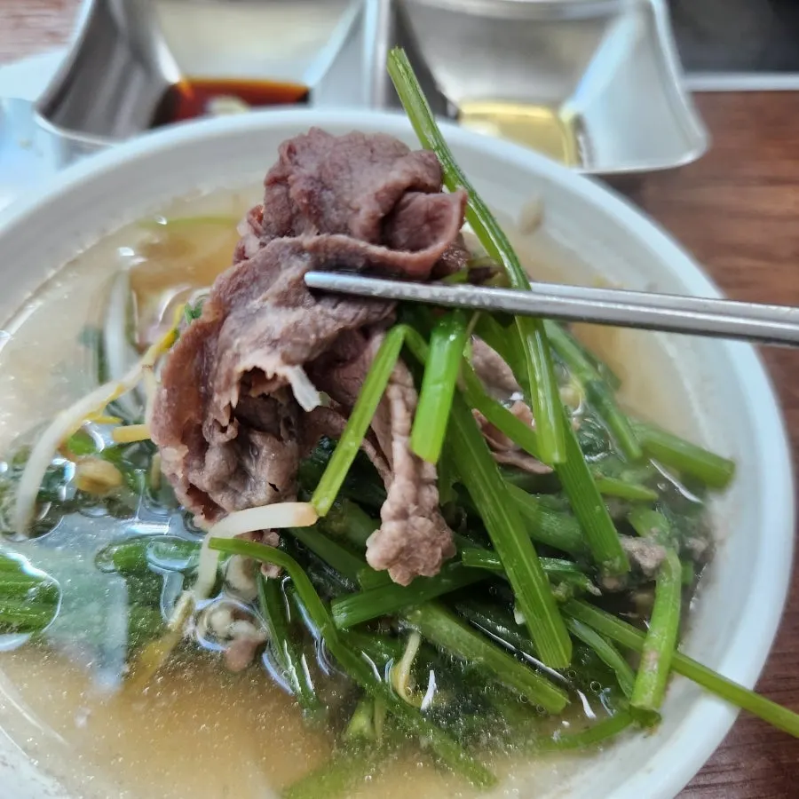 Clear broth topped with minari and bean sprouts