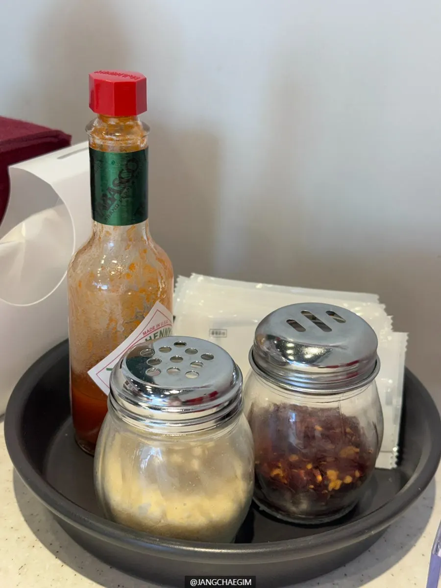 Hot sauce, parmesan cheese, and crushed red pepper set on the table