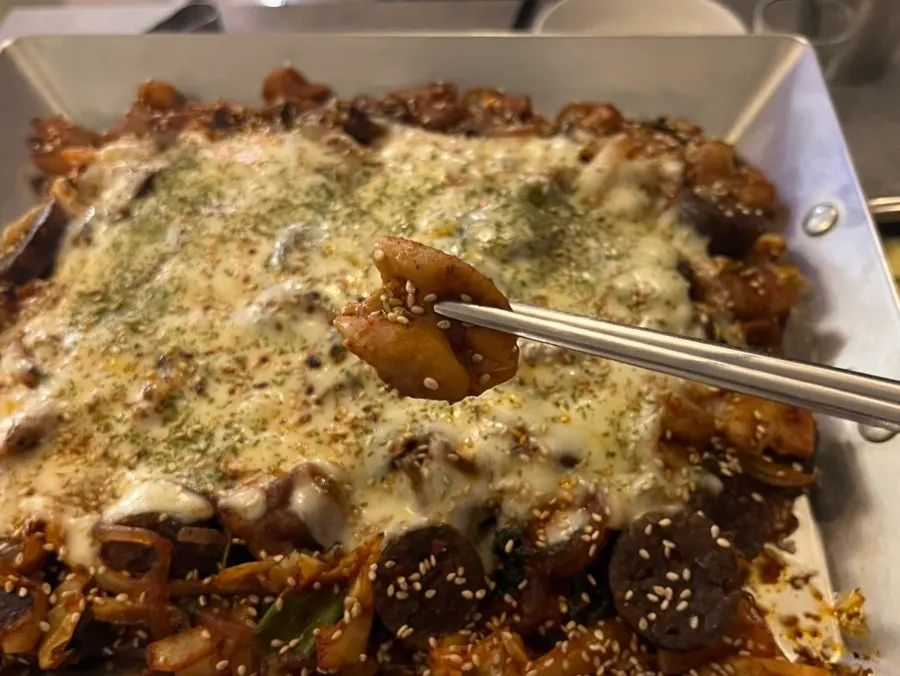 Gopchang lifted with tongs, cheese stretching