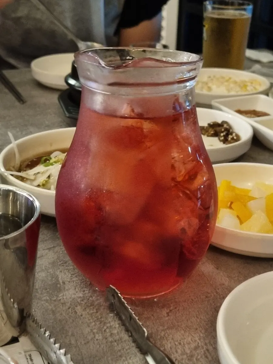 A glass of hongcho soju poured from the pitcher