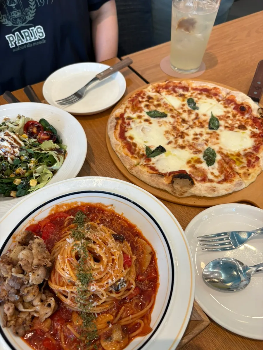 Table with pasta, pizza, salad, and ade