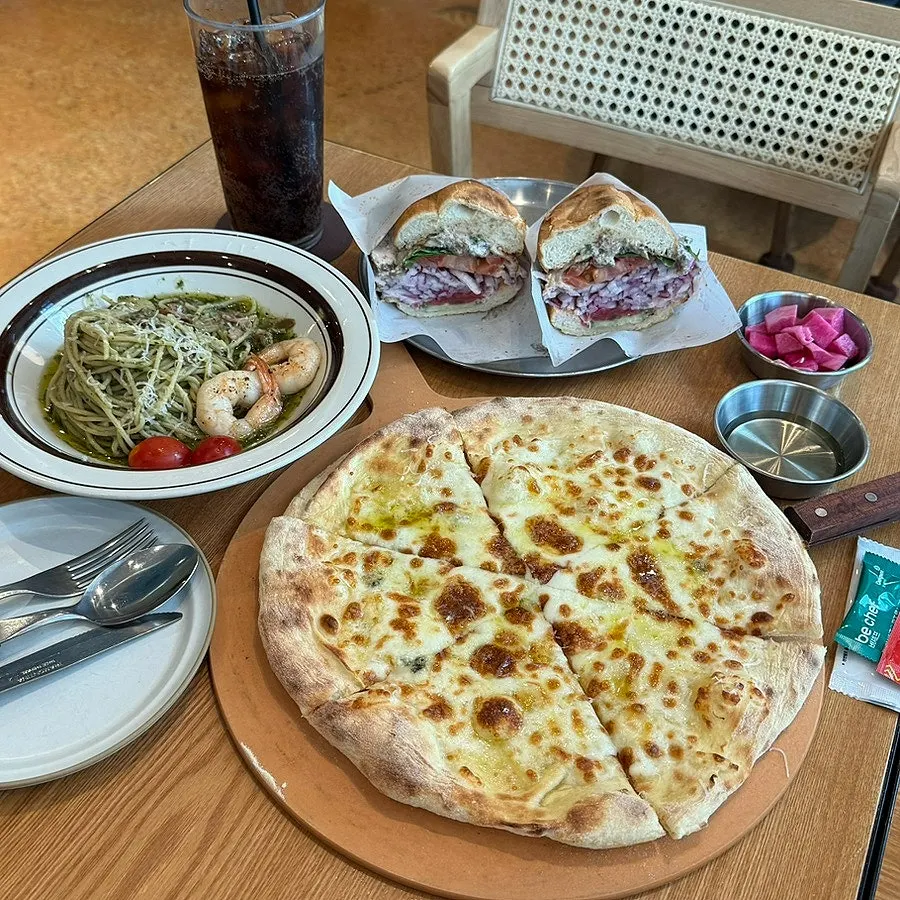 Pizza, pasta, and sandwich laid out on the table