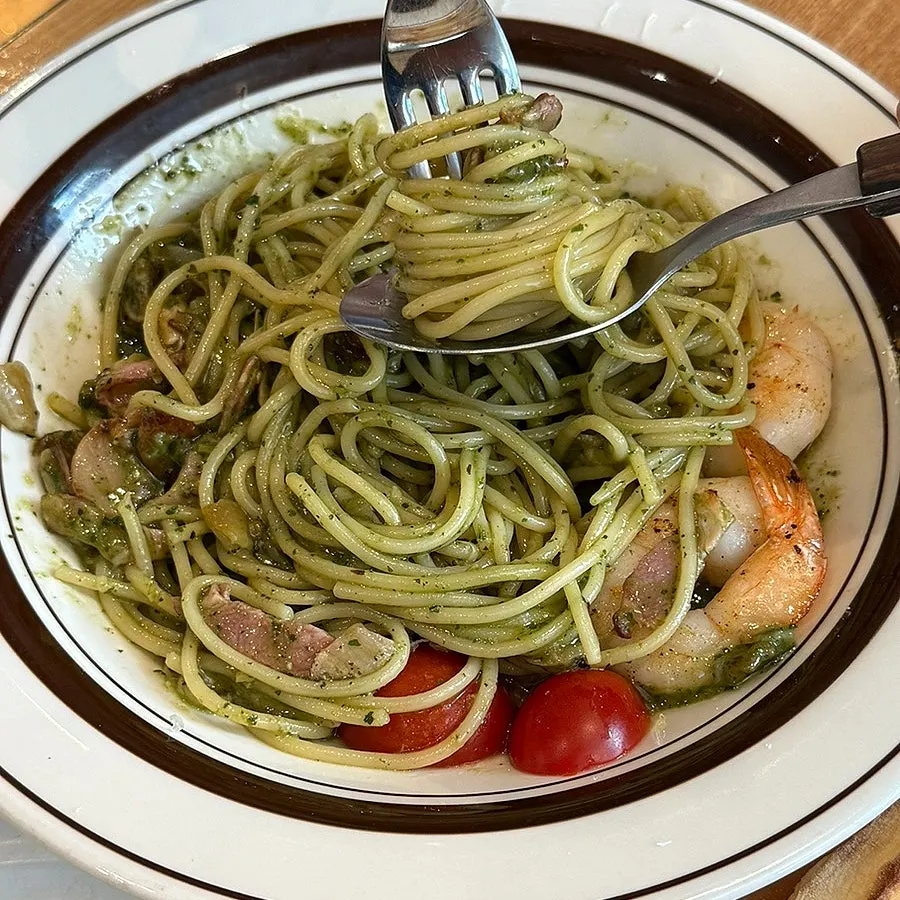 Basil oil pasta noodles lifted on a fork