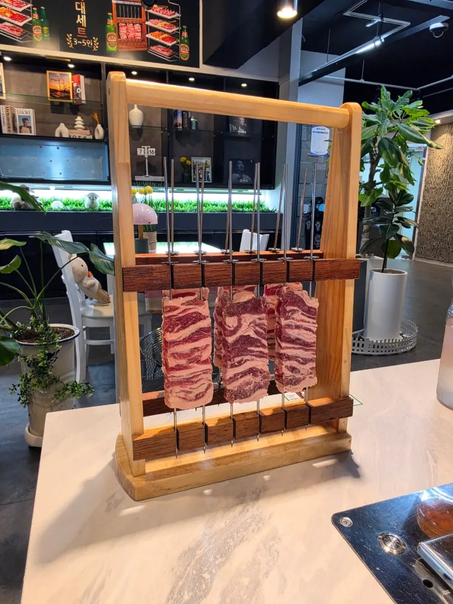 木製スタンドに掛かった厚切りラムリブ串