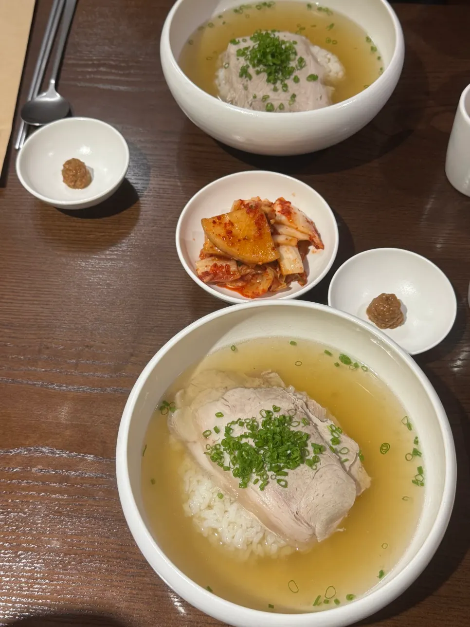 Table setting with doenjang, kkakdugi, kimchi, and a bowl of Wolhadong gomtang