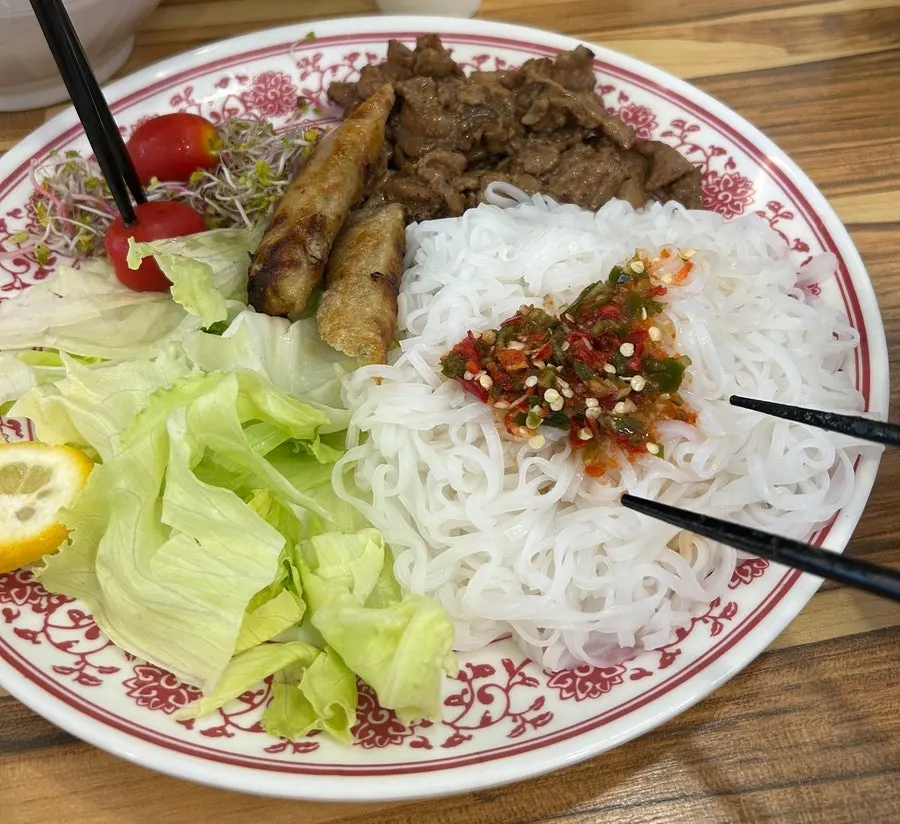 把面拌进酱汁中吃分猪肉米线的样子