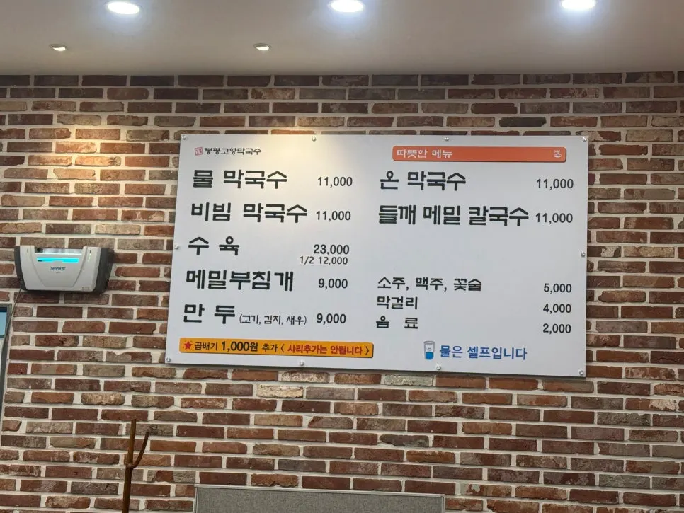 Menu board on the wall listing makguksu and perilla buckwheat kalguksu
