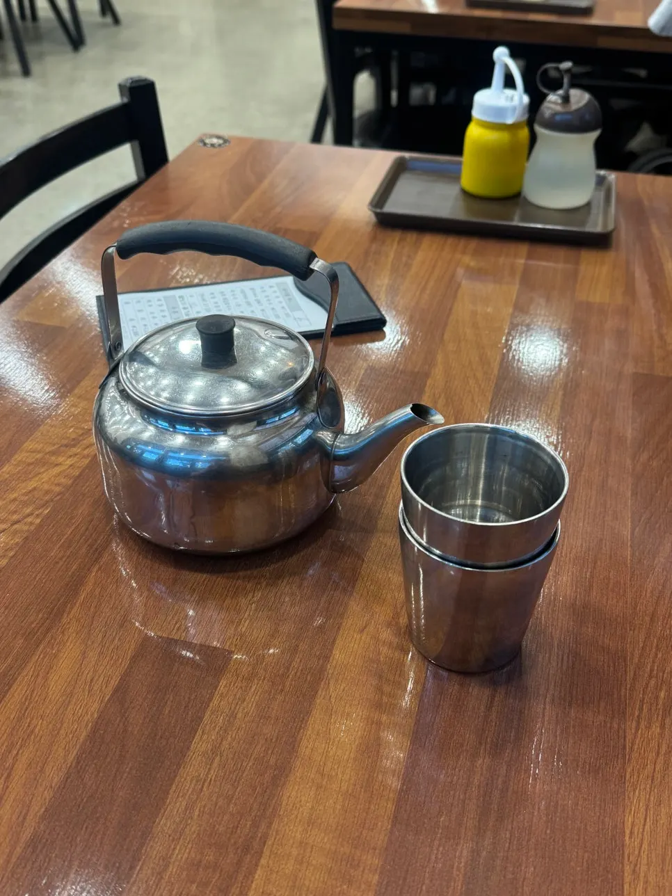 Table set with stainless kettle, cups, mustard, and vinegar