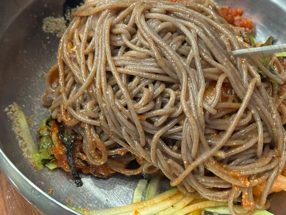 Grayish-brown buckwheat bibim makguksu mixed thoroughly with sauce