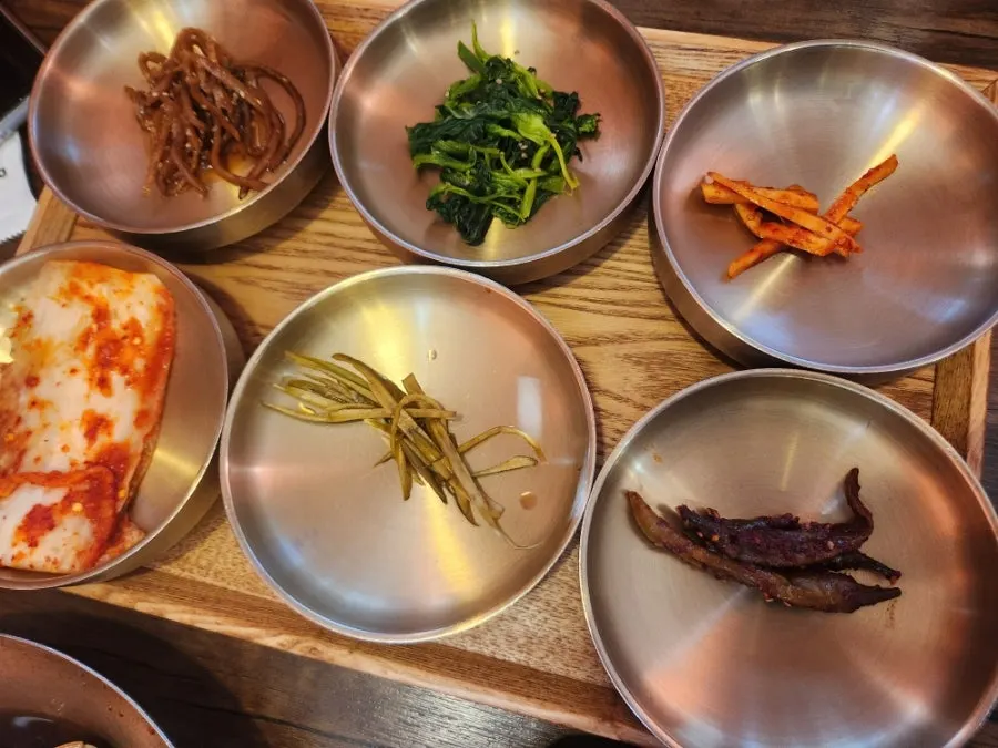 Close-up of hanjeongsik side dishes like braised potatoes and doraji namul