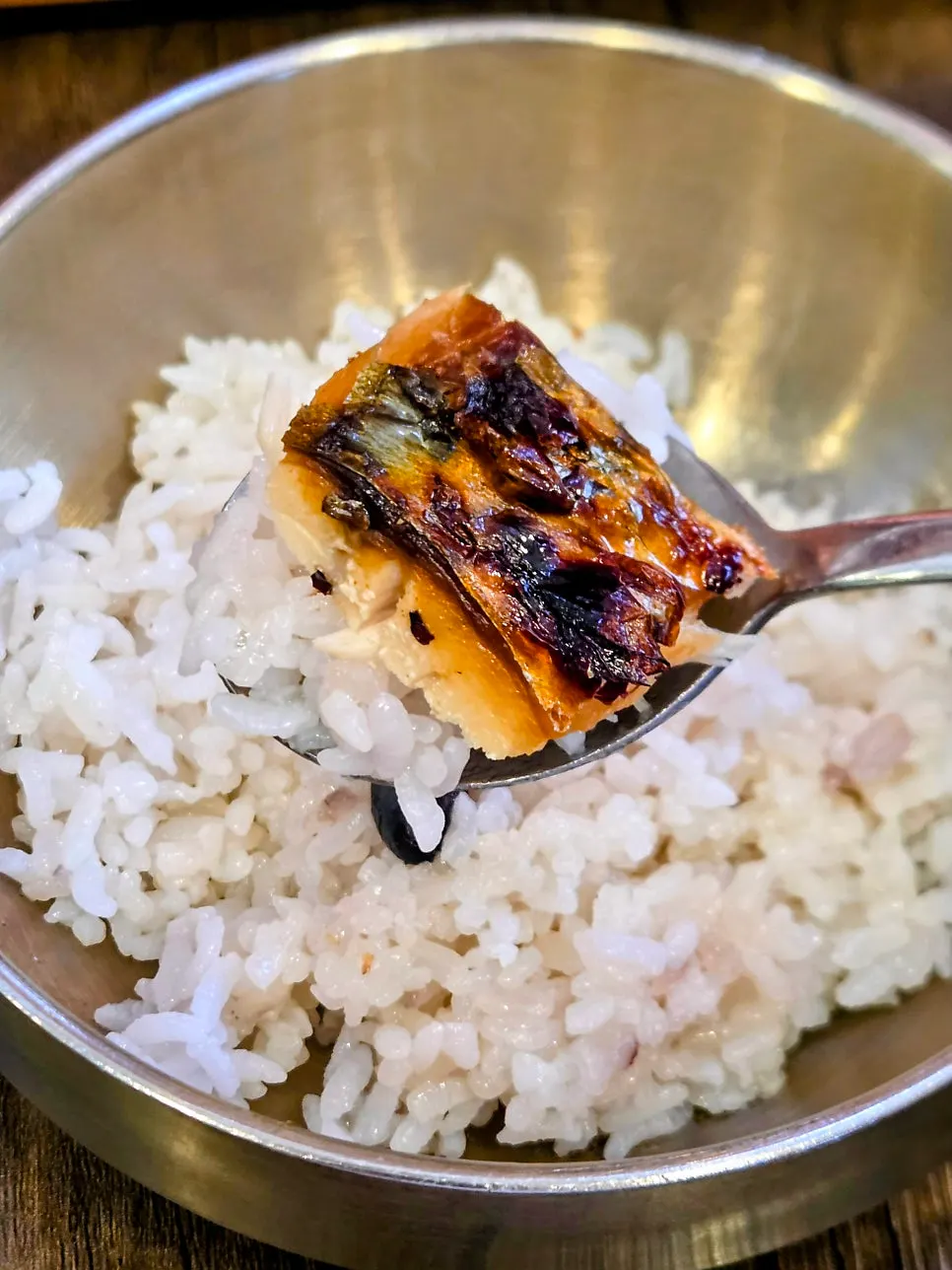 A spoonful of hot stone-pot rice eaten with grilled mackerel