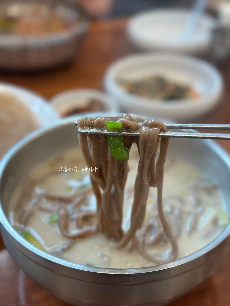 Ongsimi and buckwheat kalguksu noodles lifted up on chopsticks