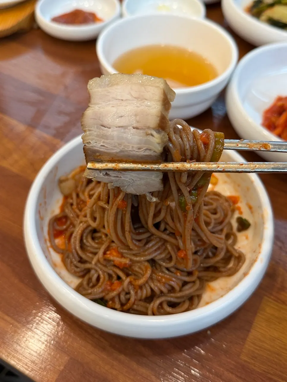 젓가락으로 들어 올린 비빔막국수 메밀면