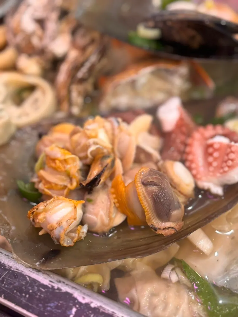 Clam meat and broth set on a fan mussel shell