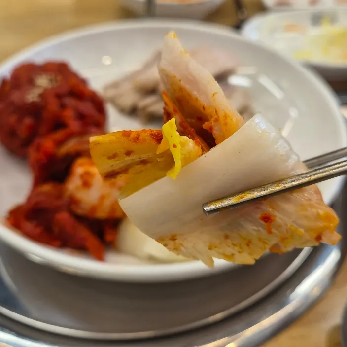 황금배추에 보쌈과 김치를 올린 한 쌈