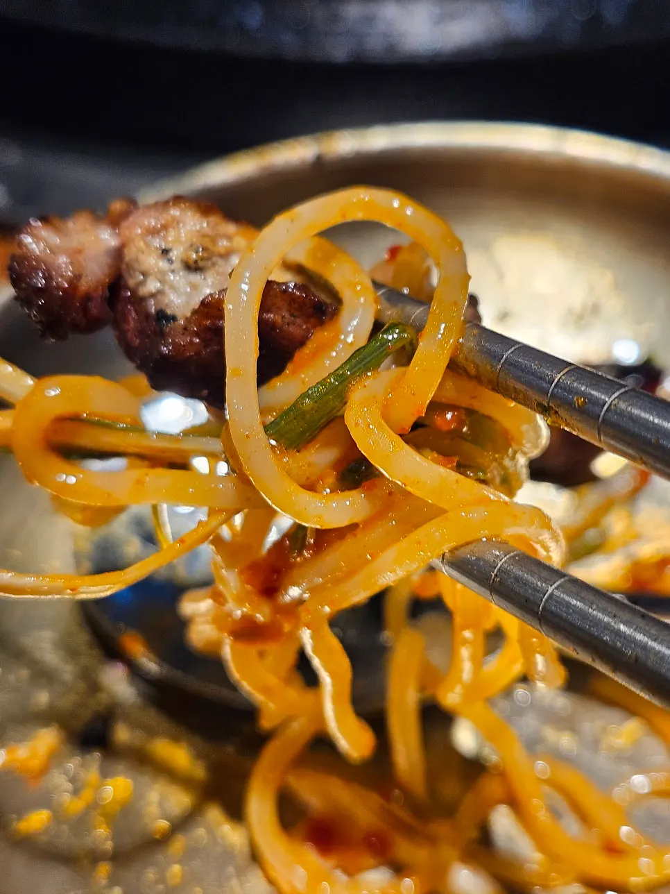 A piece of meat topped with mustard leaf kimchi and pickled onion