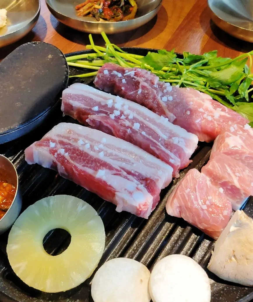 불판에 올린 돼지고기와 곁들이 채소