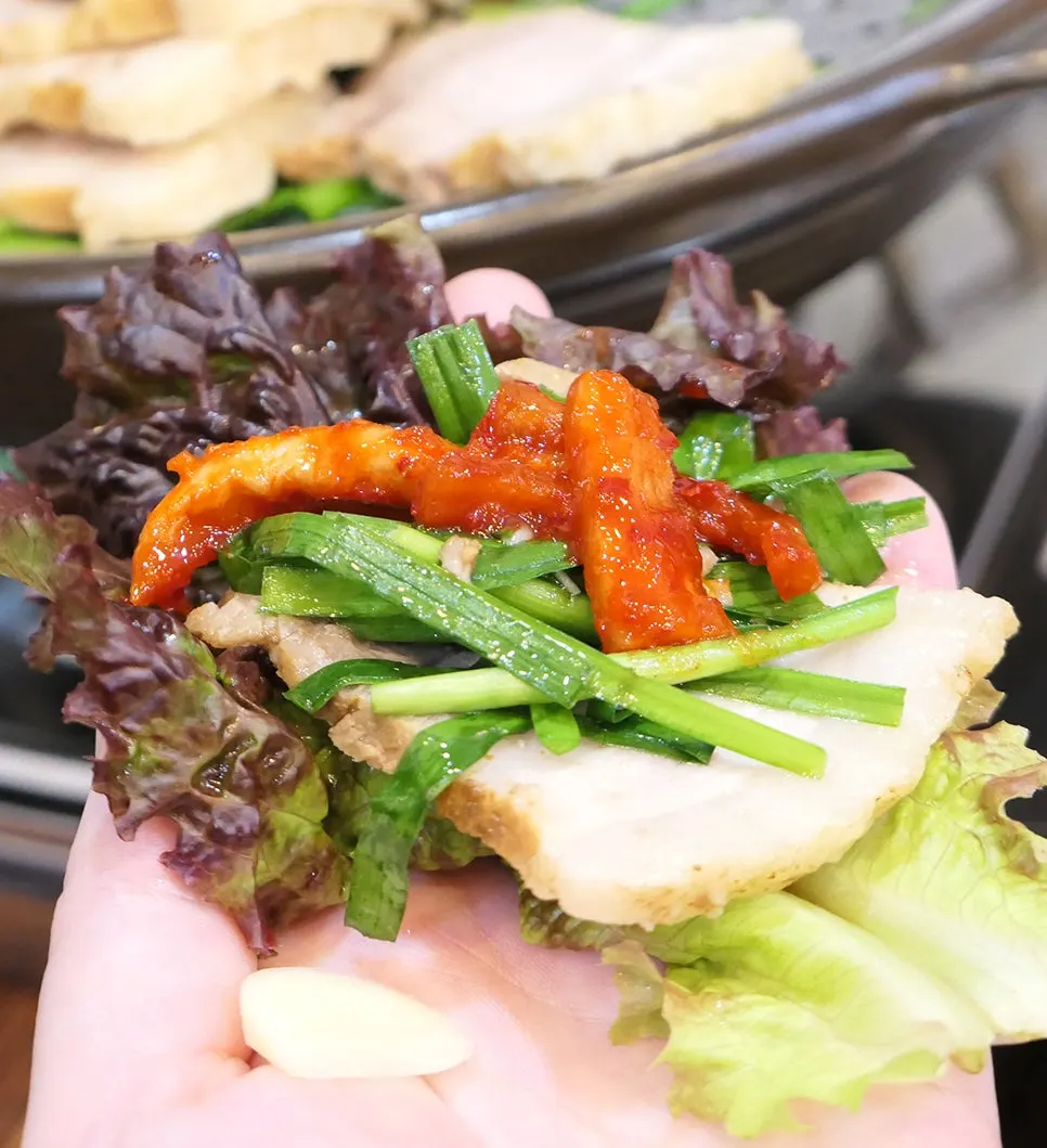 A slice of pork topped with bossam kimchi