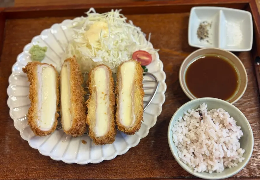 Mozzarella cheese stretching from the cheese katsu lifted with chopsticks
